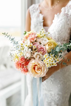 A delicate bridal bouquet with pink and peach roses, white flowers and eucalyptus.