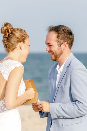 A romantic beach wedding couple shares a tender moment in front of the ocean.