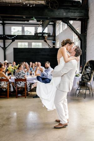 Wedding couple performs dramatic dip dance move on reception floor.