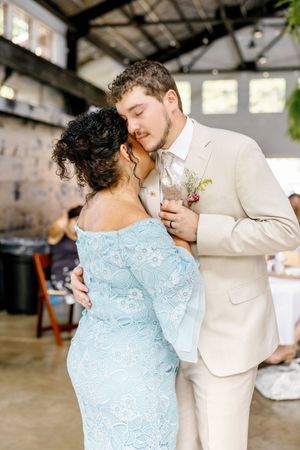 Couple shares tender dance moment with guest in blue dress at indoor reception.