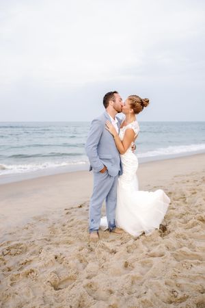 Couple shares romantic moments on sandy beach during sunset wedding photoshoot.