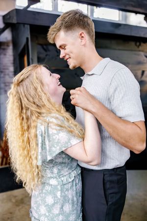 A couple shares a joyful moment while dancing together indoors.