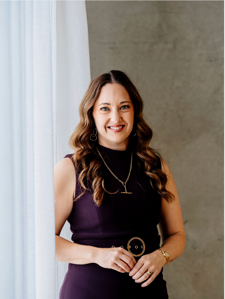 A photographer wearing a floral dress captures moments in an outdoor garden setting with natural lighting.