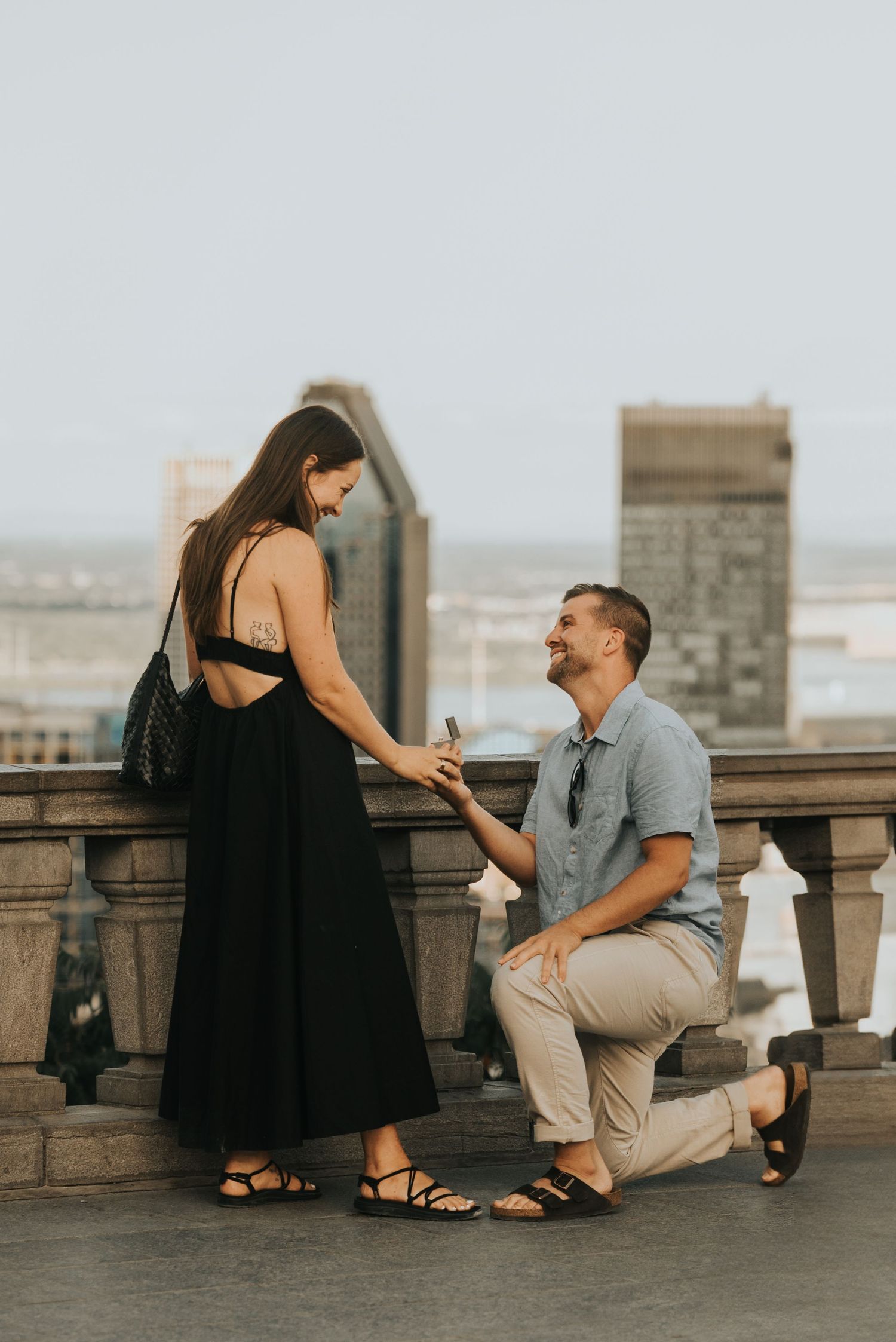 A romantic proposal sequence showing a couple on a rooftop as someone gets down on one knee to propose marriage.