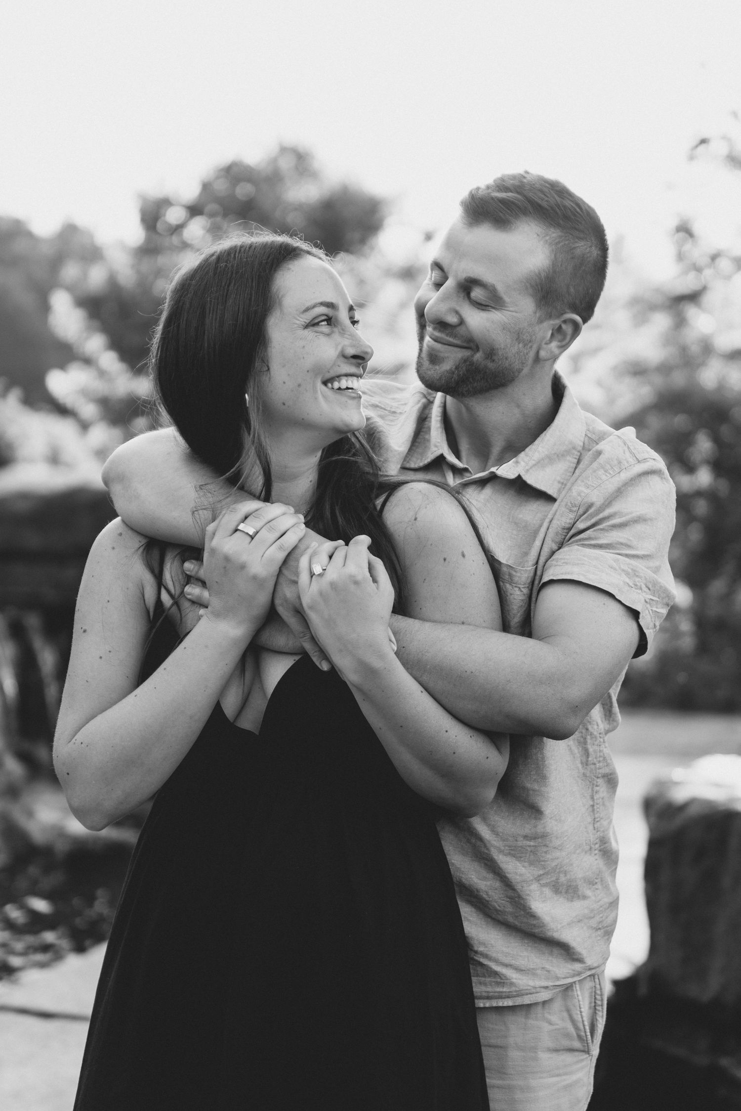 A candid black and white photo series capturing a couple laughing and embracing in natural outdoor lighting.