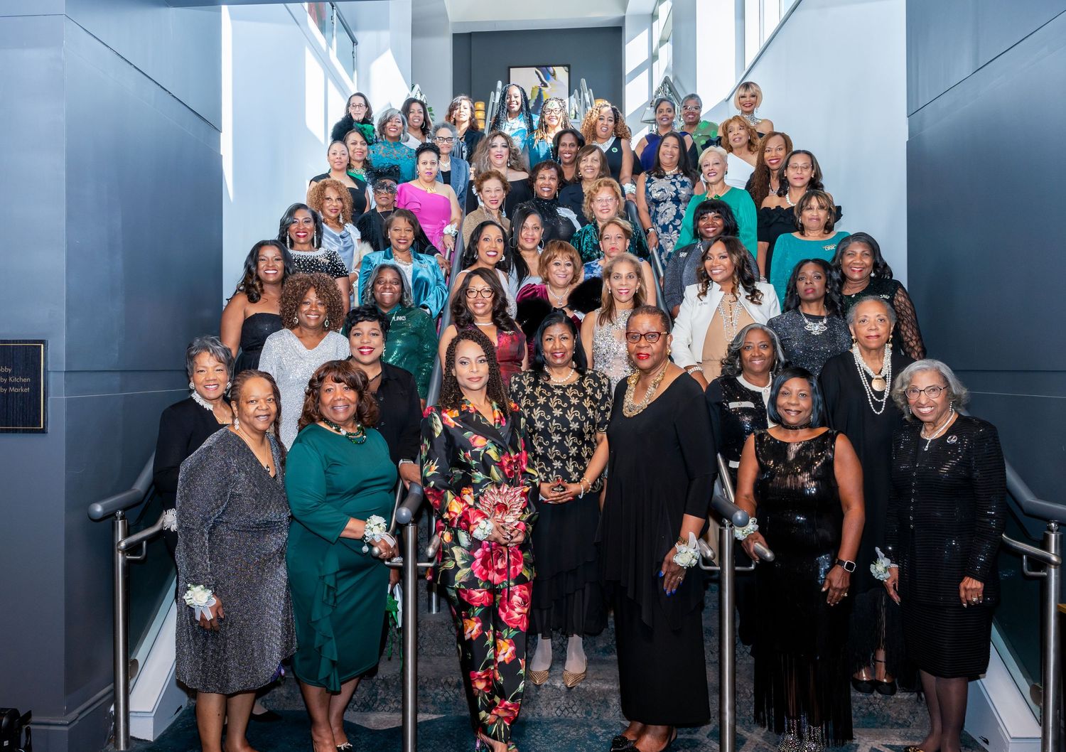 Large group photo of event attendees gathered on stairs wearing formal attire.