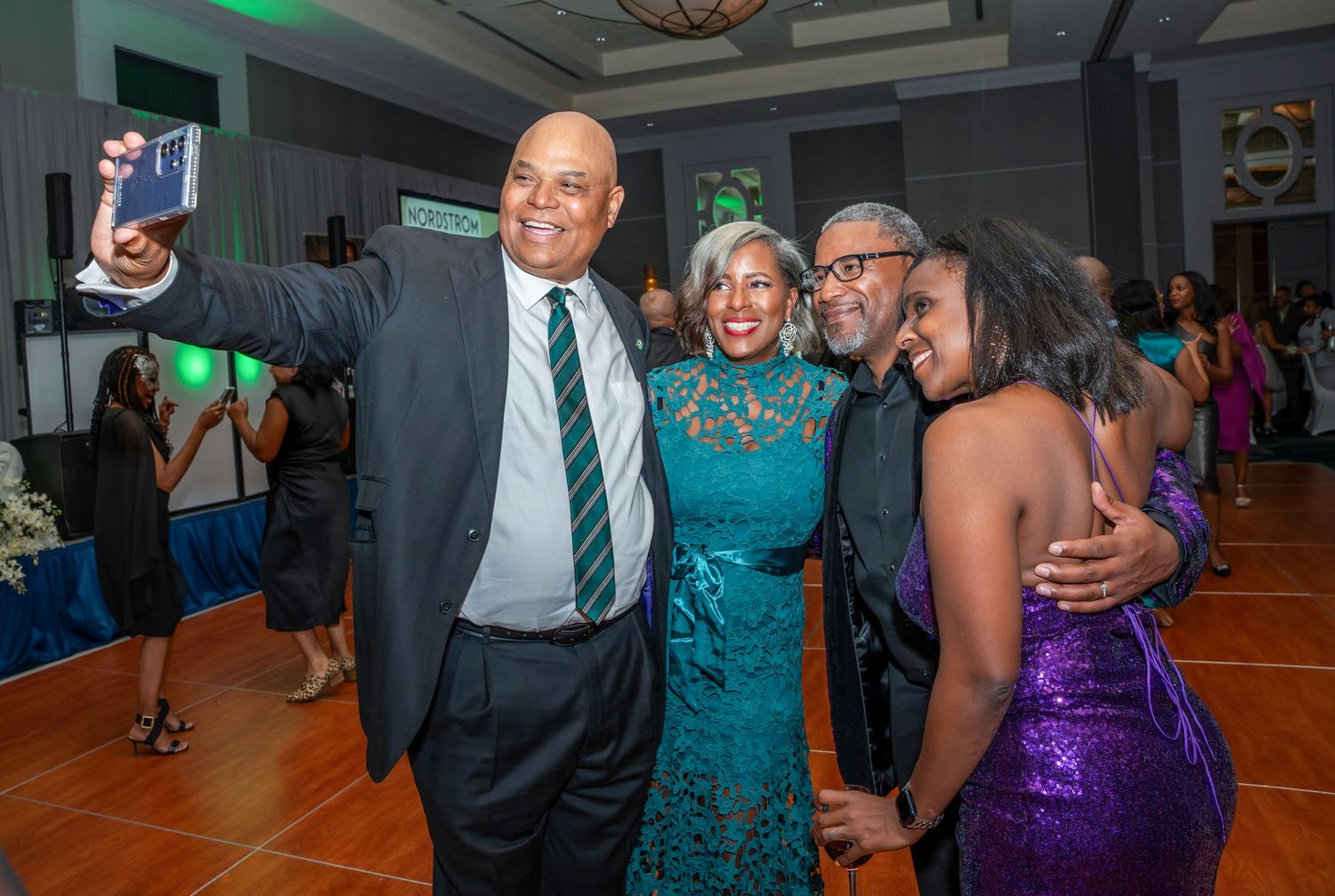 Group poses together on dance floor at formal event with elegant lighting and decor.