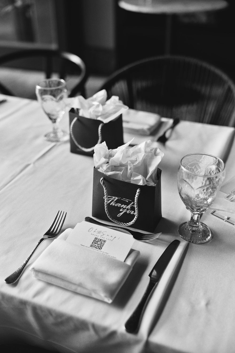 Elegant place setting at formal dinner with white tablecloth, crystal glasses, and black name card holder.