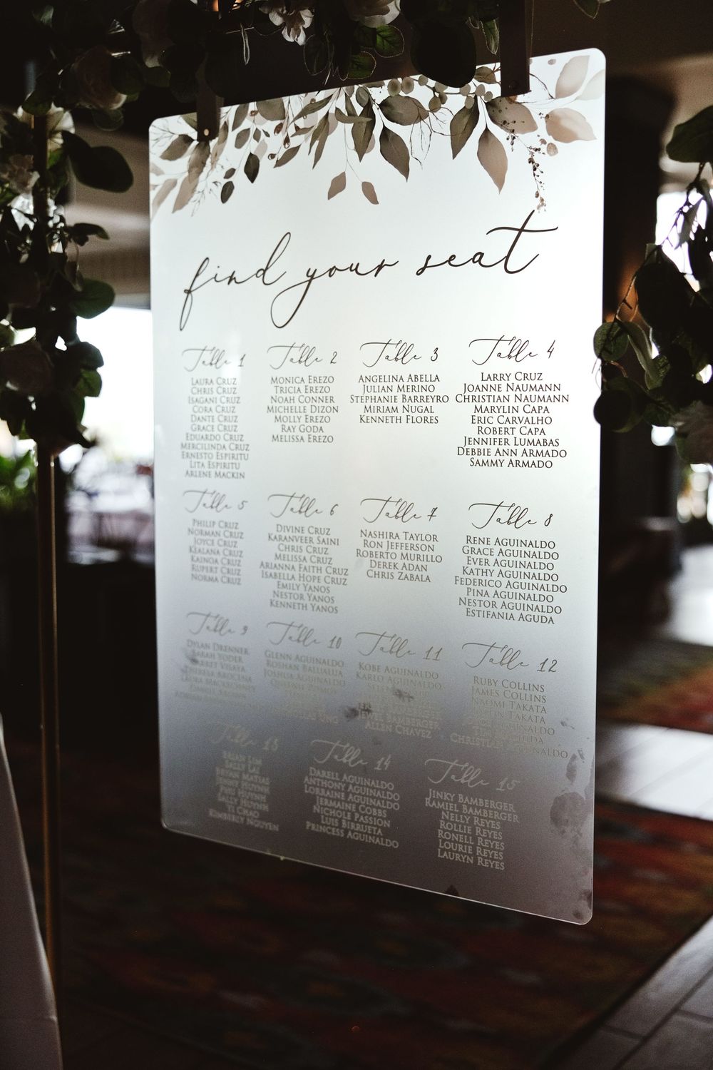 Wedding seating chart display with table assignments printed in elegant script on white boards.