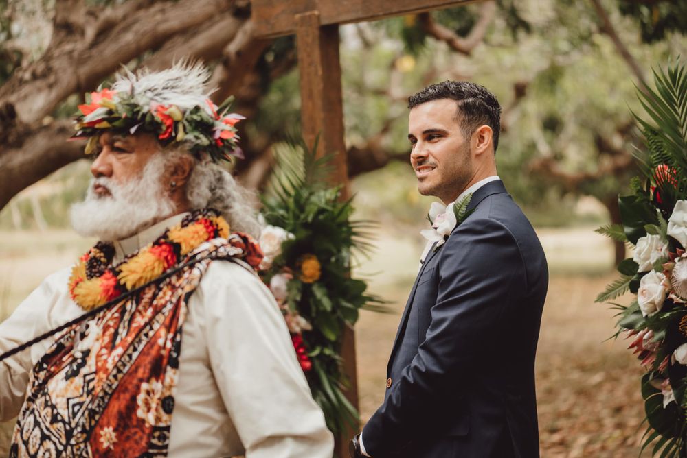 Outdoor wedding ceremony setup with floral arrangements and wooden arch under tropical trees.