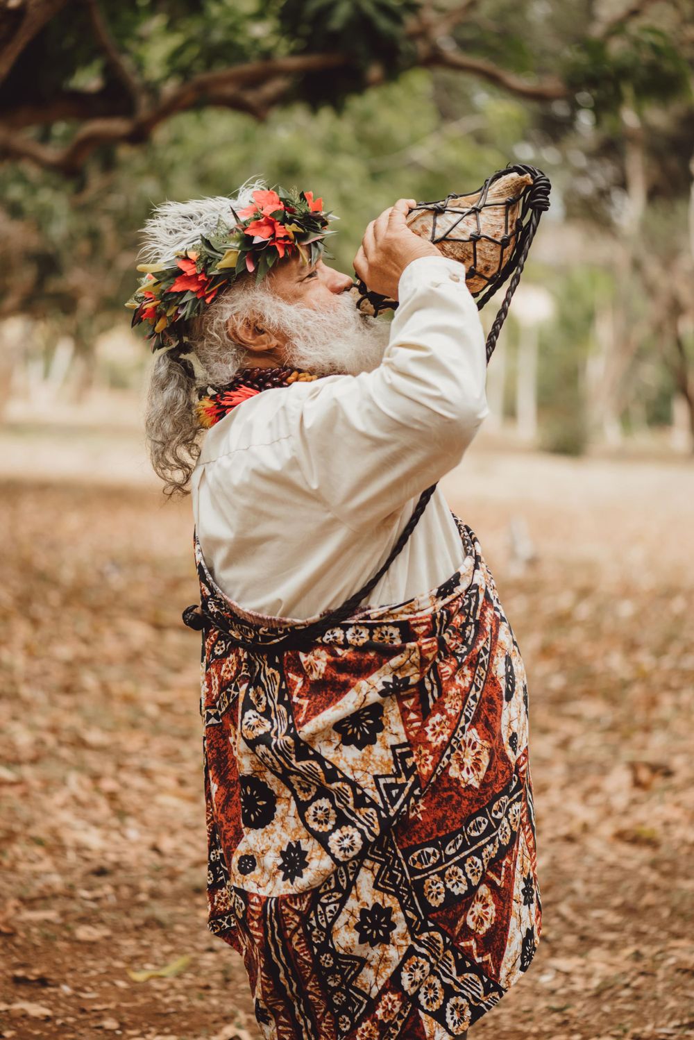 Wedding guest in floral dress swings joyfully on a tree swing during outdoor celebration.