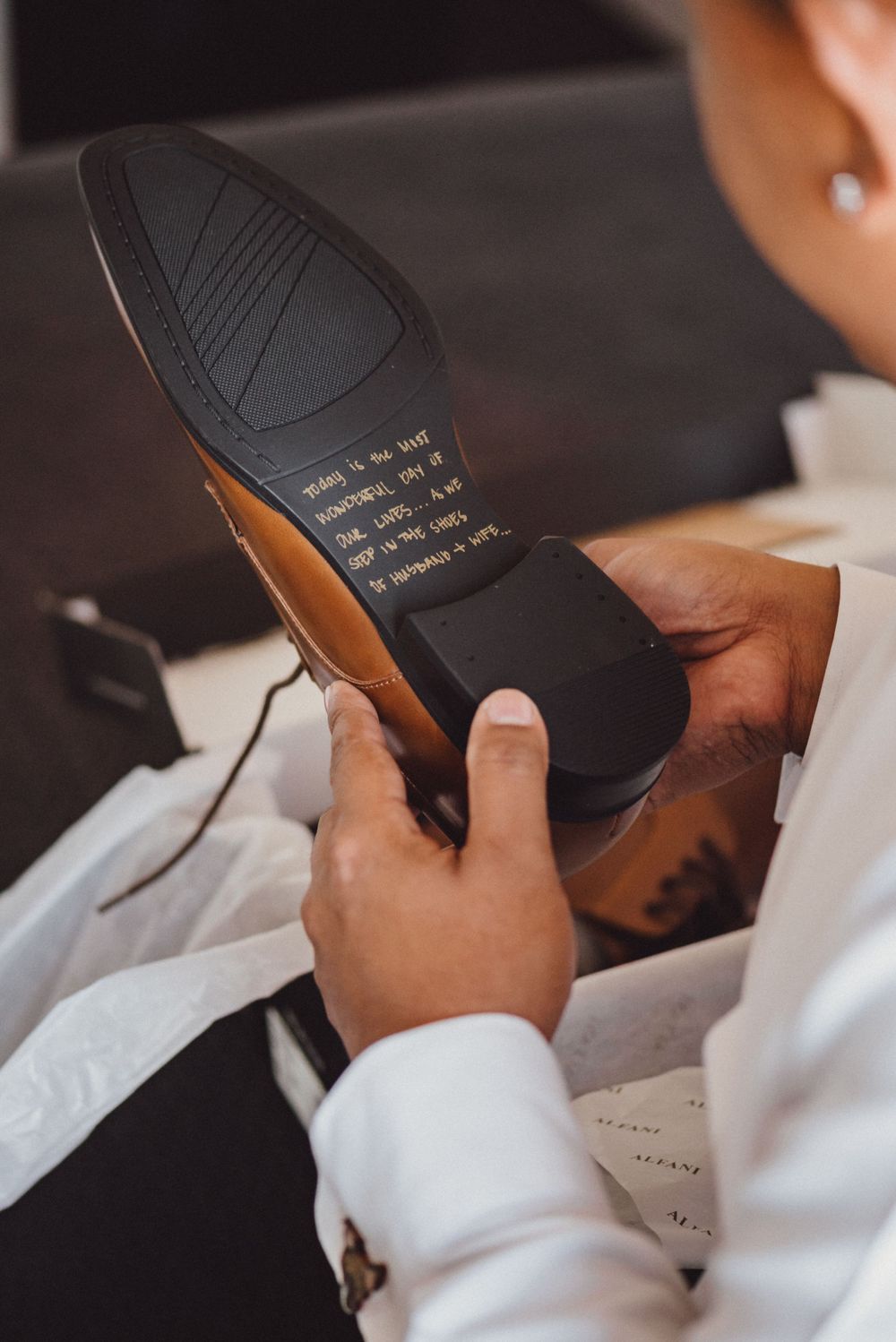 Close-up of handwritten message on the sole of formal black shoes.