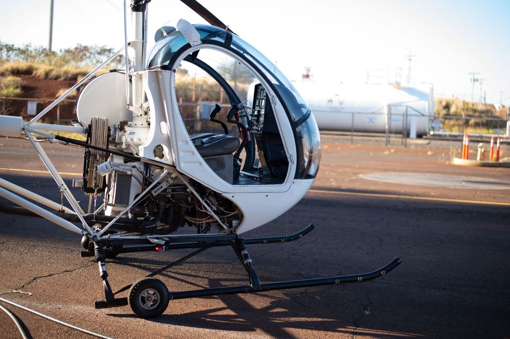 Helicopter parked on tarmac with mountains visible in background.