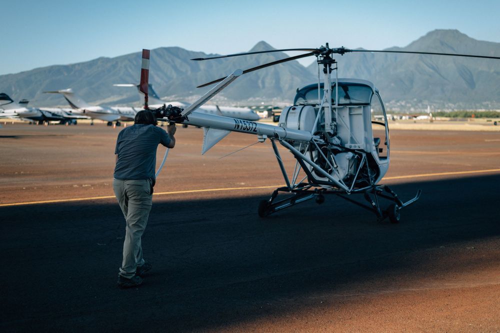 Helicopter on airfield tarmac against backdrop of desert mountains.