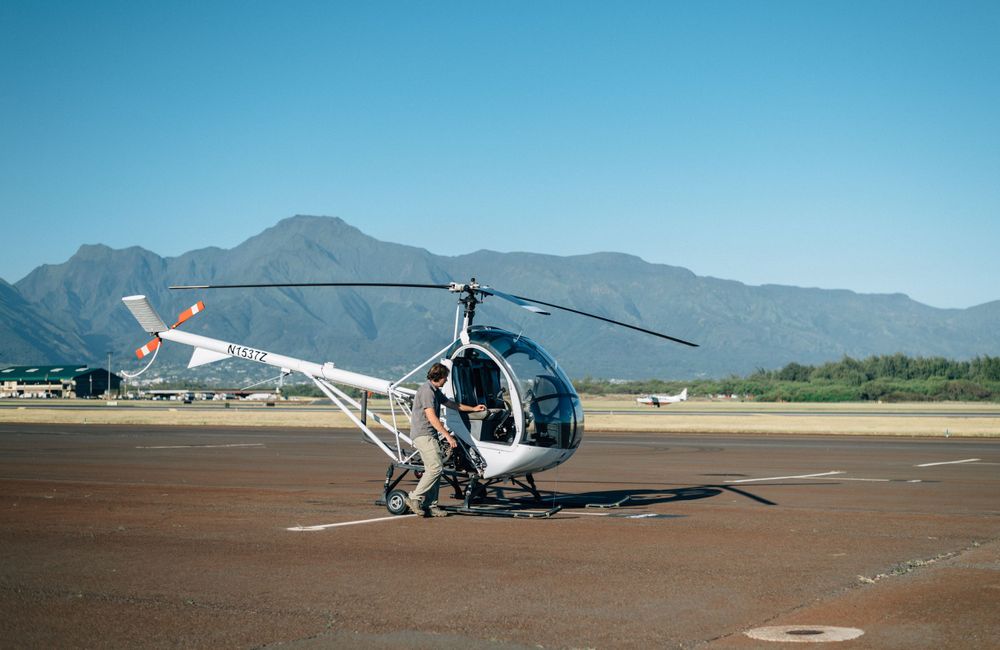Helicopter on desert runway with dramatic mountain landscape behind.