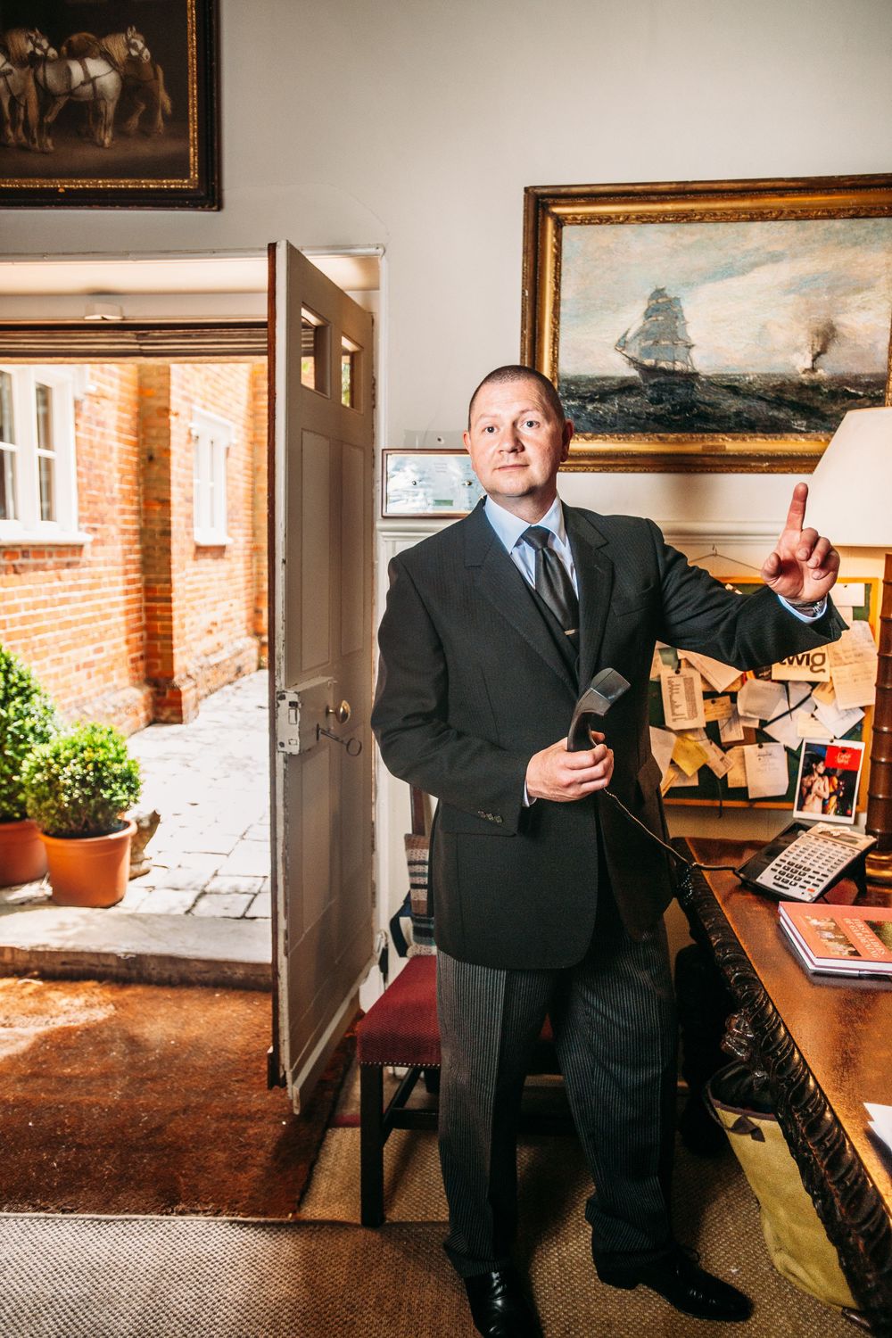 A series of six connected photos showing someone in a dark suit posing in an office setting with artwork and brick walls.