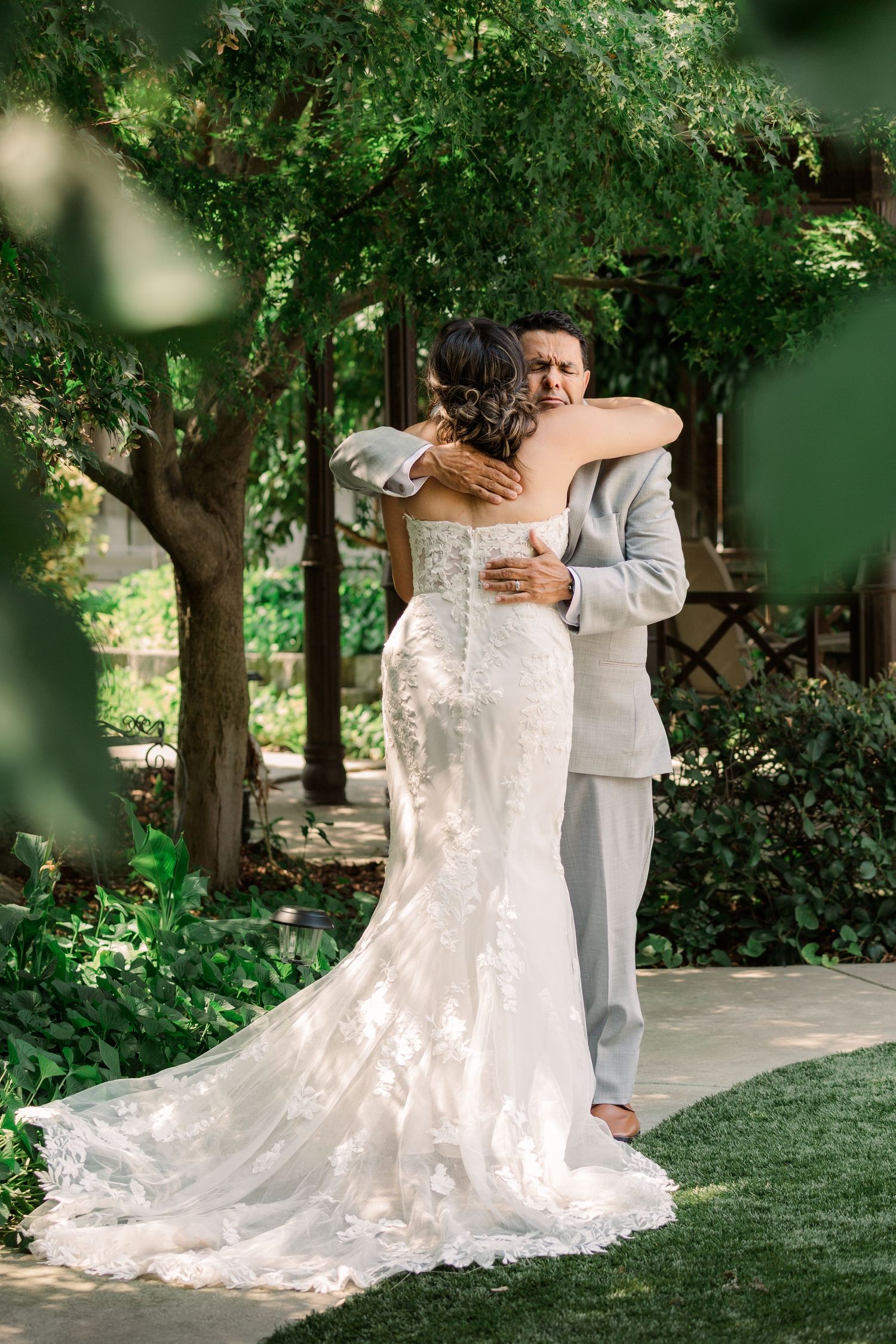 First look moment captured in garden setting with flowing white wedding dress.