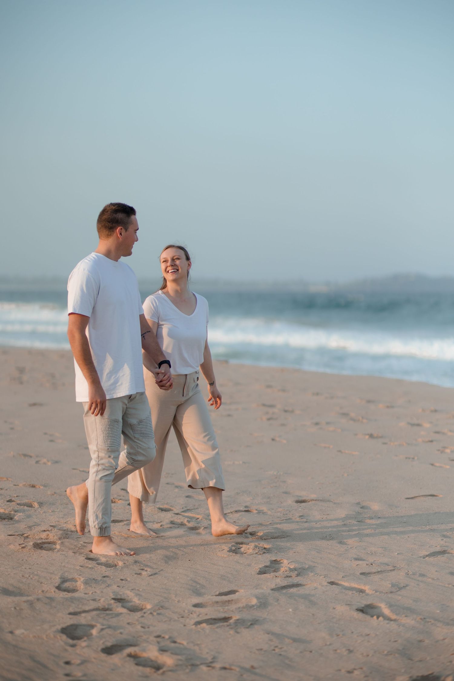 Couple walking along Windang Beach in soft evening light