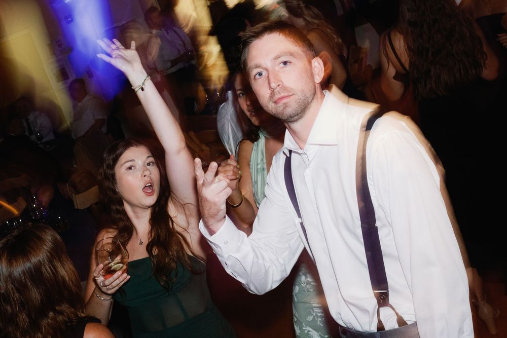 People dancing and having fun at a nightclub with purple lighting and white shirts.