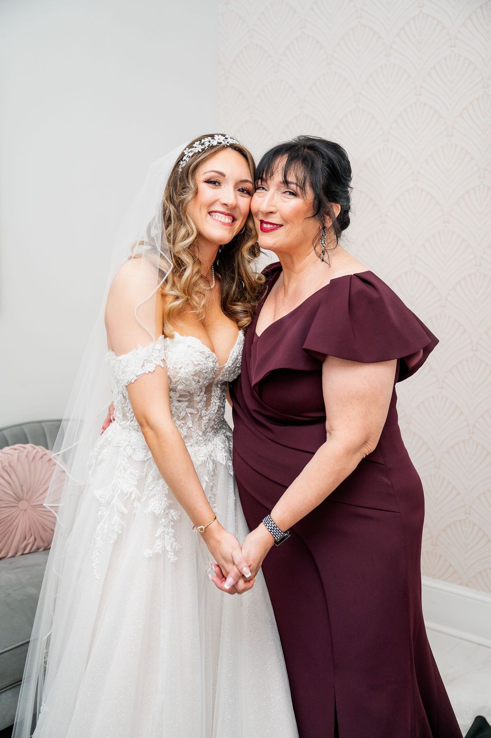 Tender moment between bride in white gown and attendant in burgundy dress.