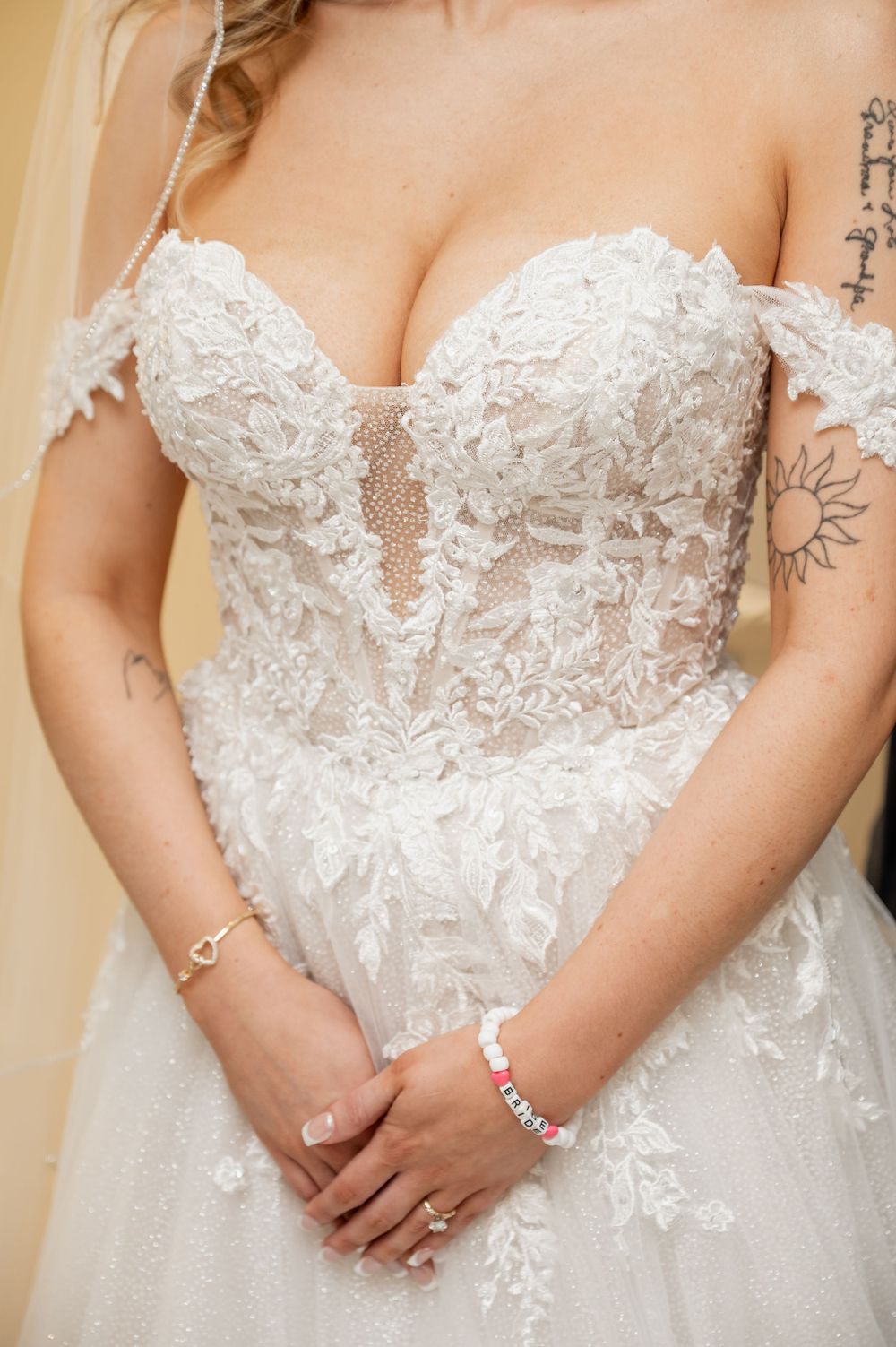 Close-up details of an ornate white lace wedding dress bodice with delicate floral appliques.