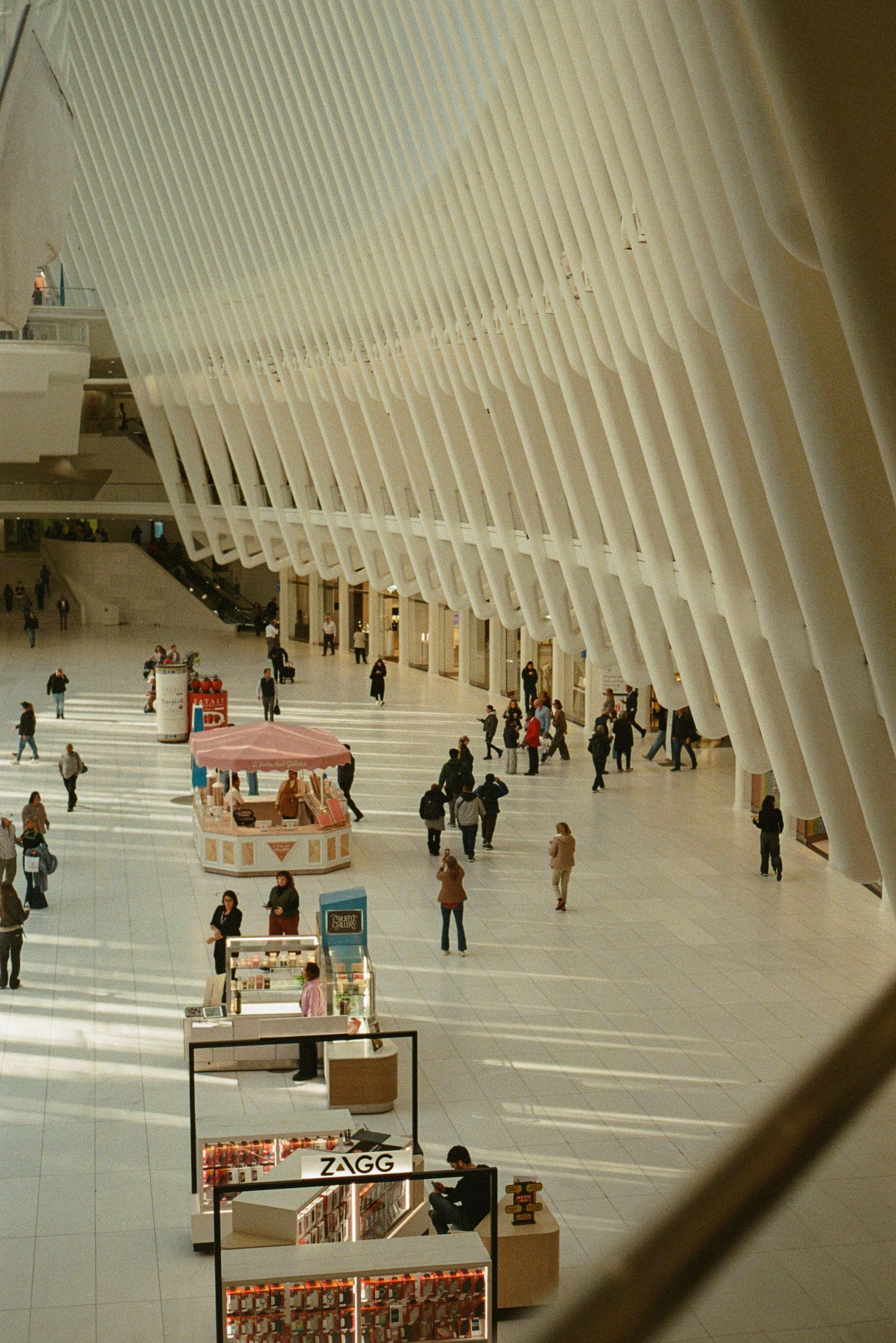 People walking through the modern white architectural interior of the Oculus transportation hub in New York City.
