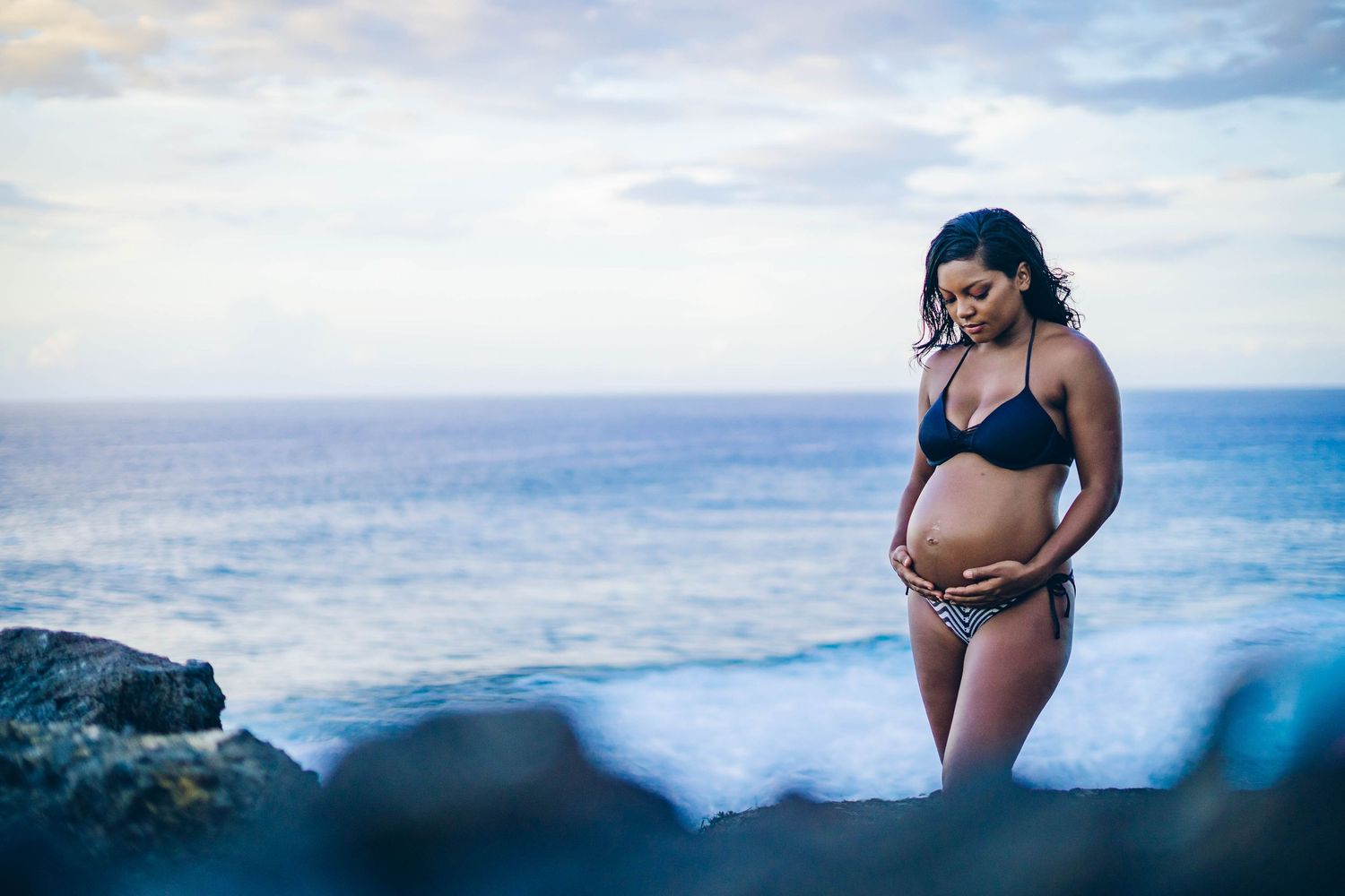 A series of black and white maternity photos showing a pregnant belly in a lace dress against a dark background.