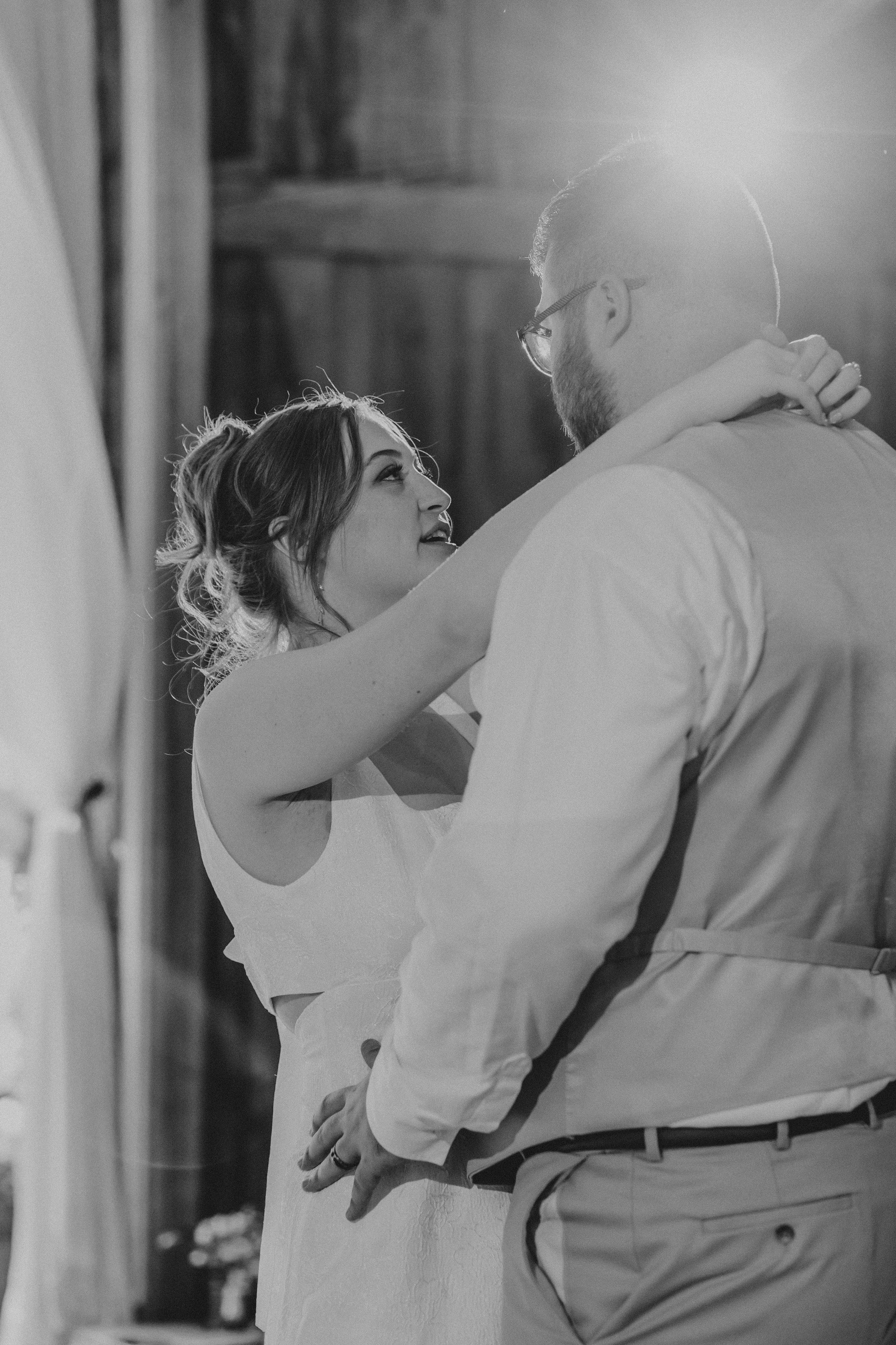 A bride and groom share an intimate moment while dancing, with soft lighting illuminating their joyful expressions.