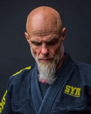 Martial artist in navy gi with yellow accents shown in dramatic studio lighting. portrait photography st louis.