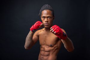 Athletic fighter in fighting stance wearing red boxing gloves against black backdrop. portrait photography st louis.