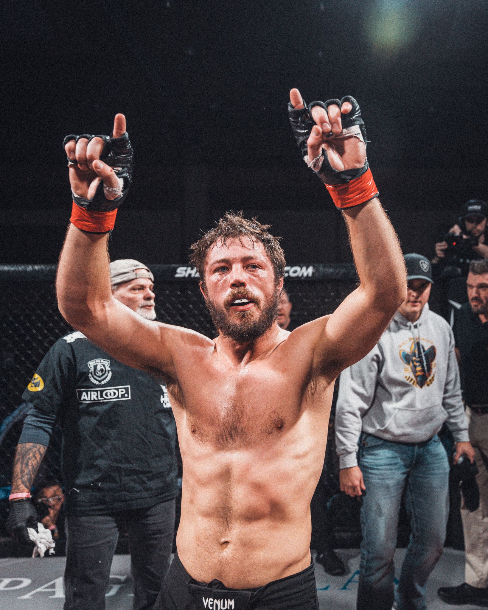 Fighter celebrating victory with raised arms in MMA octagon cage. live event photography st louis.