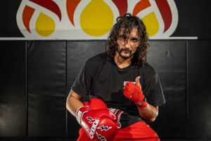 Athletic figure in black shirt holding red boxing gloves against dark background. portrait photography st louis.