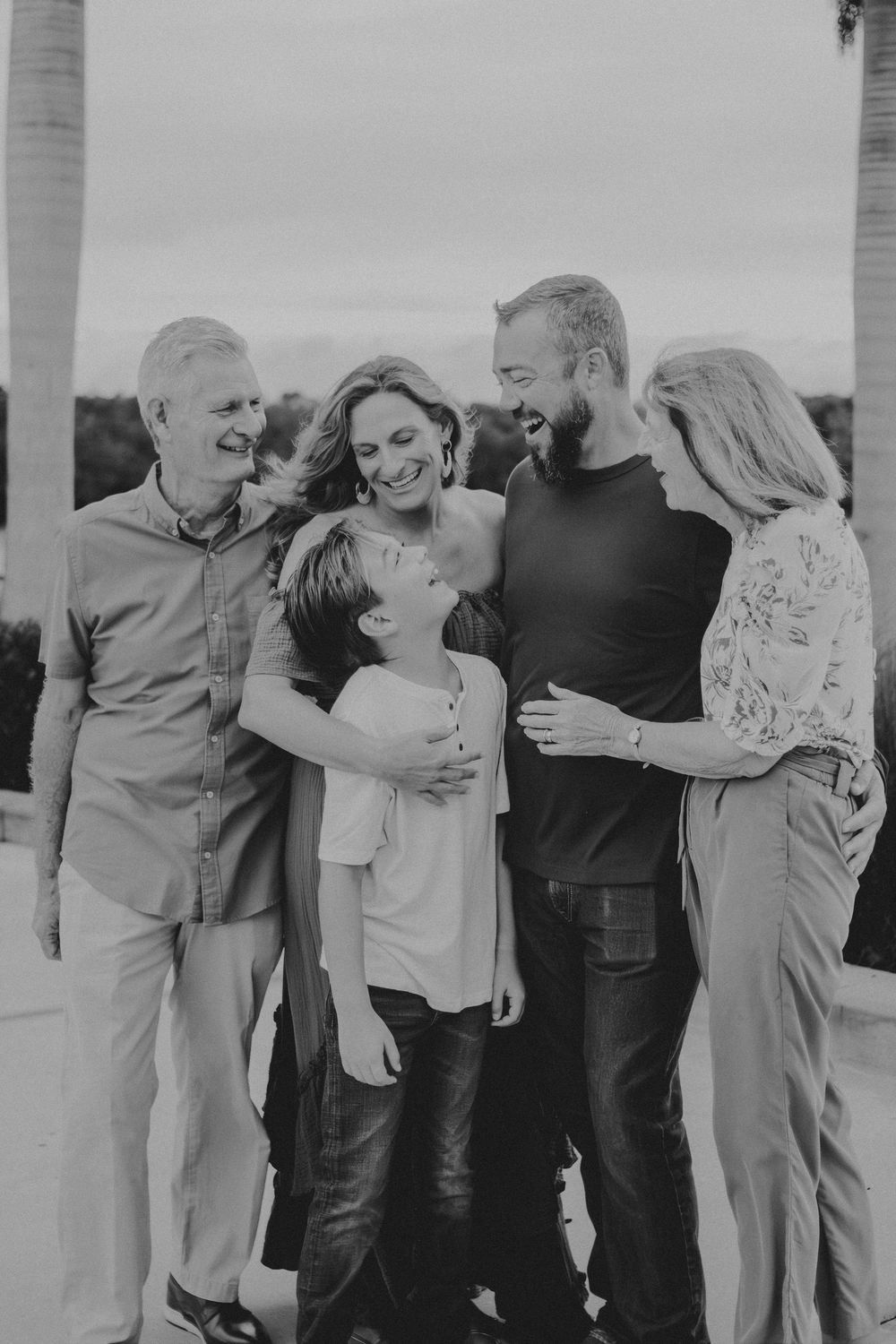 A multi-generational family shares a candid moment of laughter together in black and white.