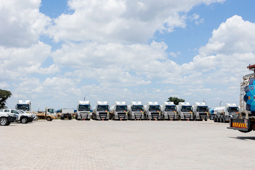 A panoramic view of RVs and campers parked along a sunny beach with white sand and blue skies.