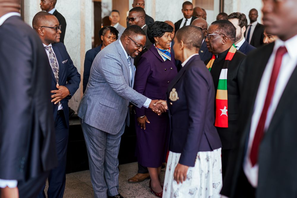 A group of formally dressed people gather in conversation at what appears to be a business or political event.