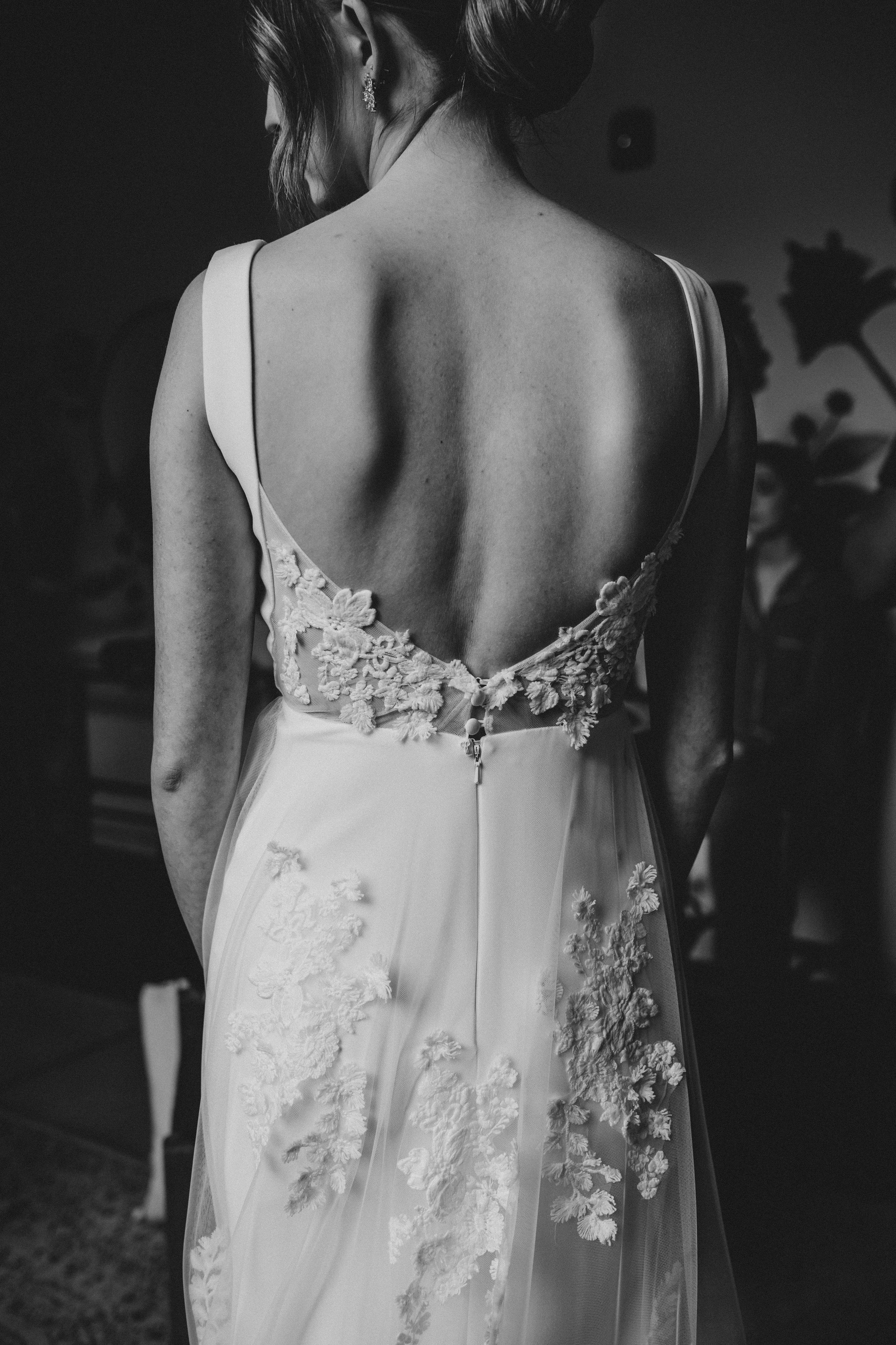 Black and white close-up detail shots of delicate lace appliques on a white wedding dress back.
