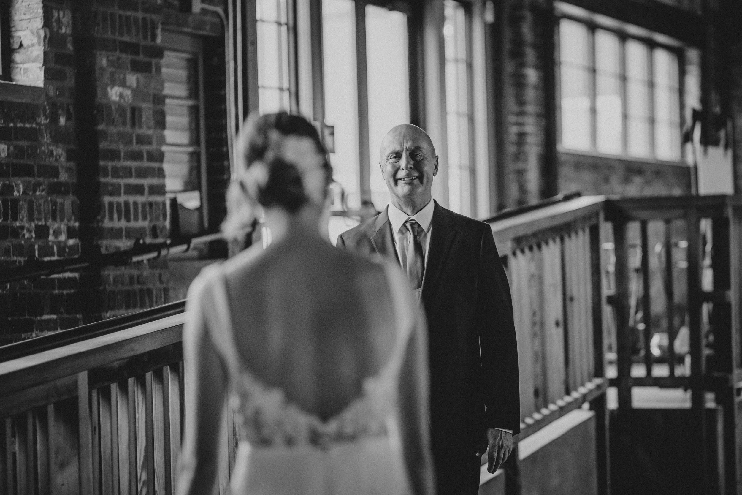 A black and white wedding photo series showing intimate moments between a couple on a porch with brick walls.