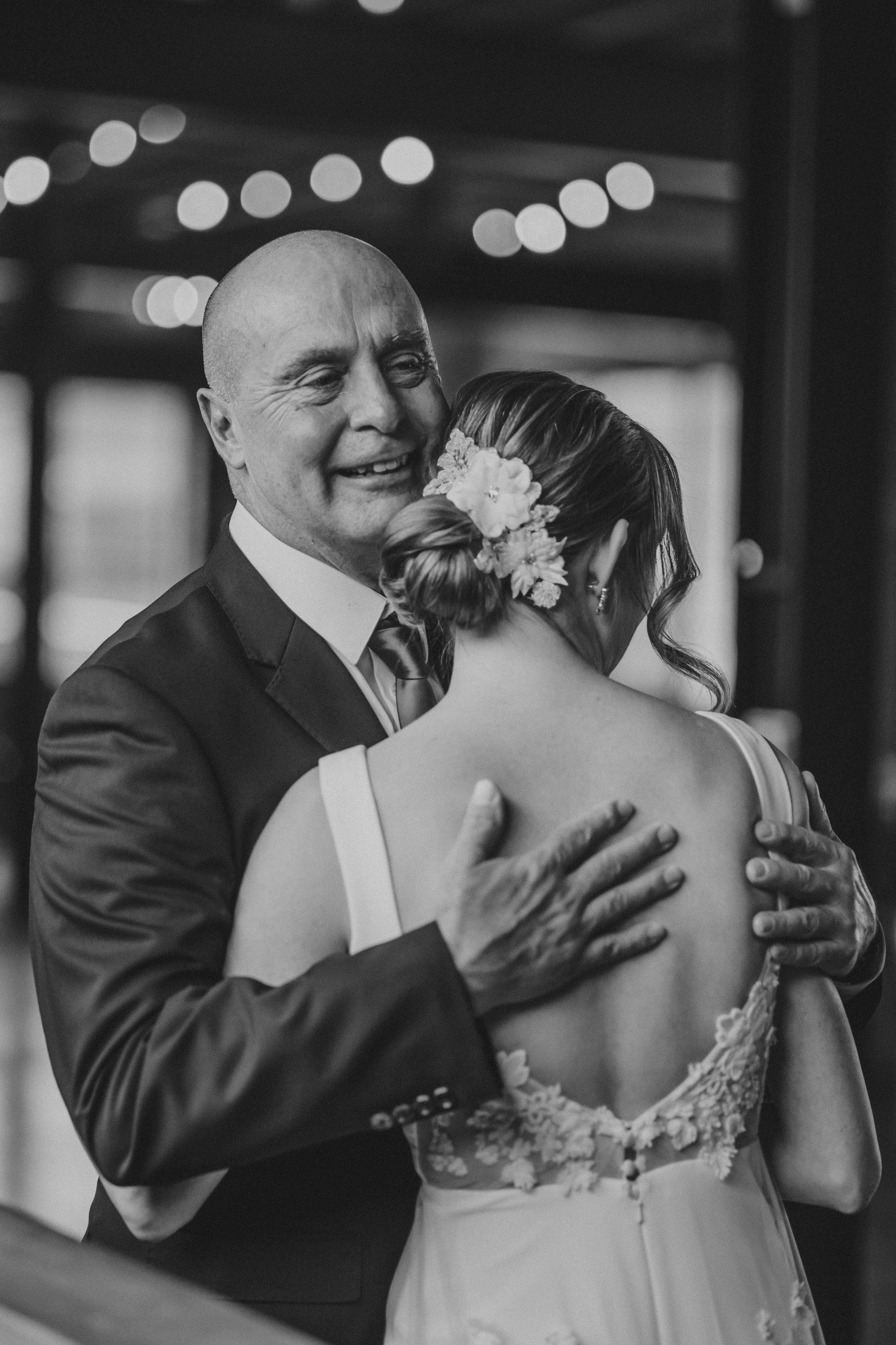 Black and white candid photos of an emotional father daughter dance at a wedding reception.