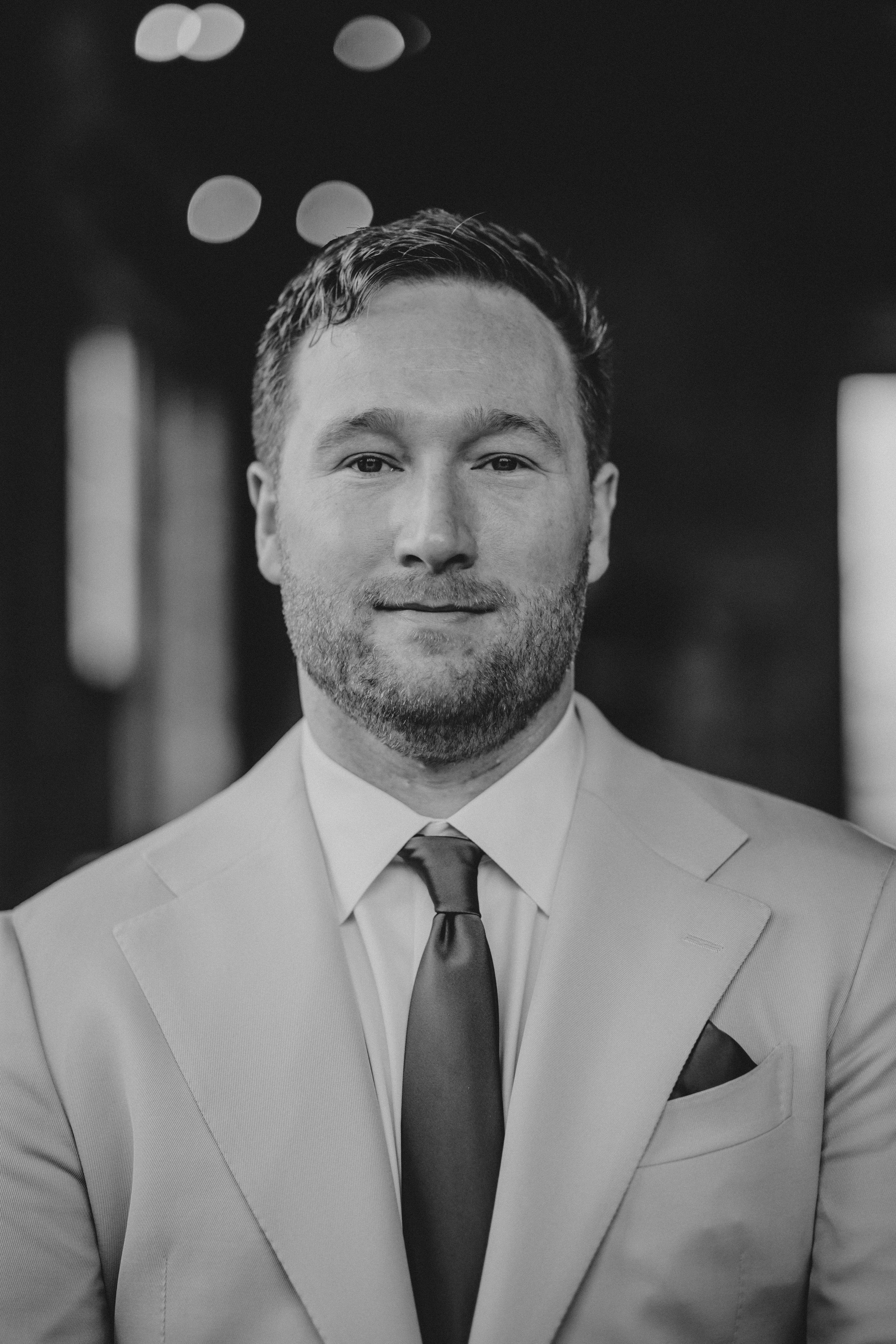 A series of black and white portraits showing someone in a light colored suit and dark tie with varying expressions.