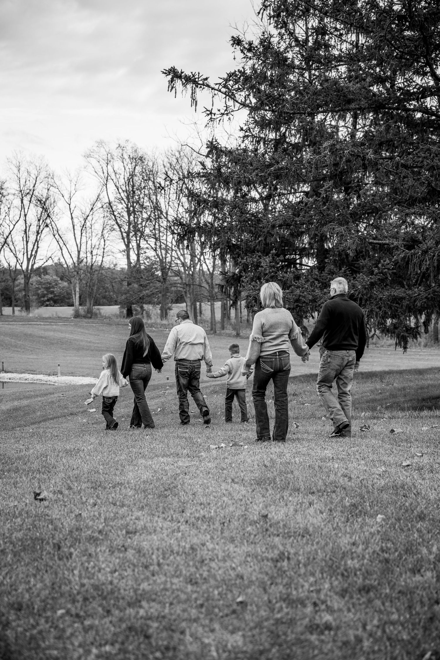 Family members walking together across a grassy hillside on an autumn day.