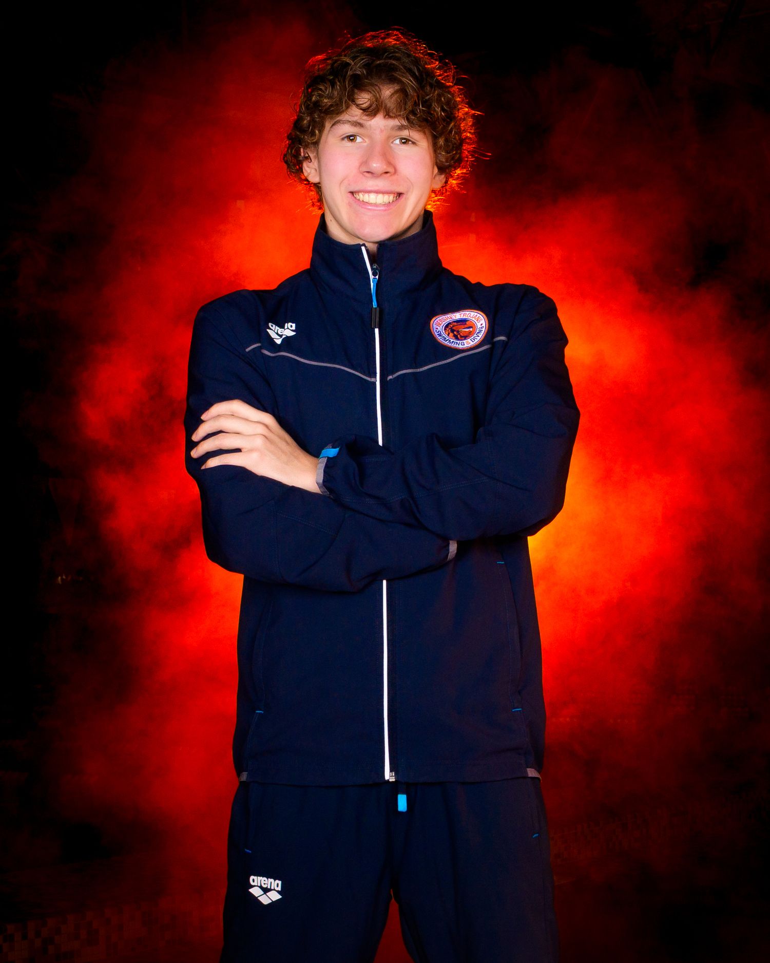 Hershey High School Trojan swimmer with blue warmup and orange fog background, by SportsFox Photography, Hershey PA