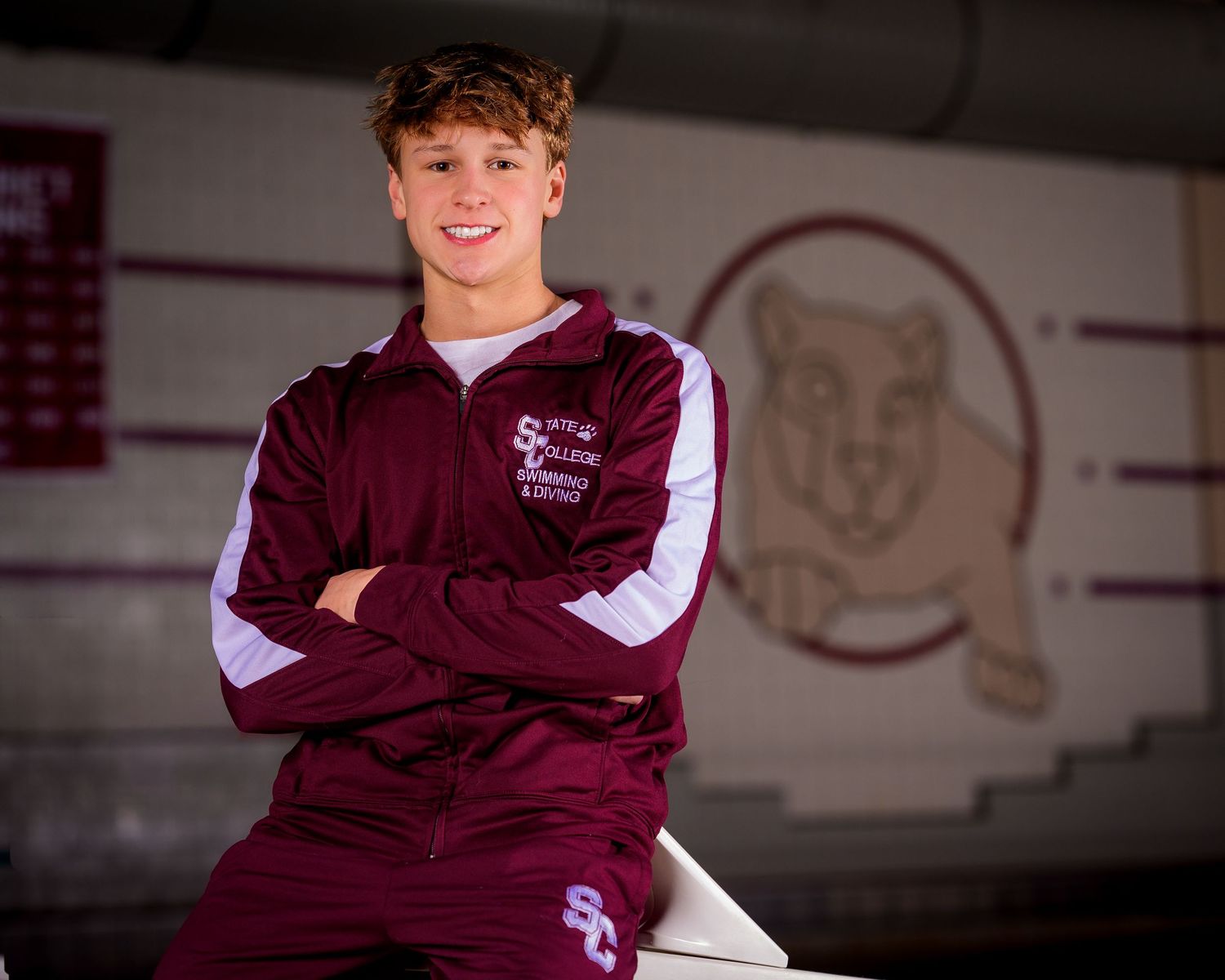 State College High School swimmer with maroon warmup and little Nittany Lion background, by SportsFox Photography, State College, PA