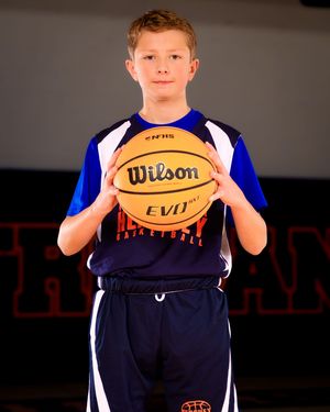 Youth basketball player in blue HYBA travel uniform holding basketball, individual portrait, team photo day.