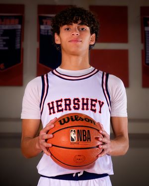 Hershey High School boys basketball player in white jersey holding basketball, individual portrait, team photo day.