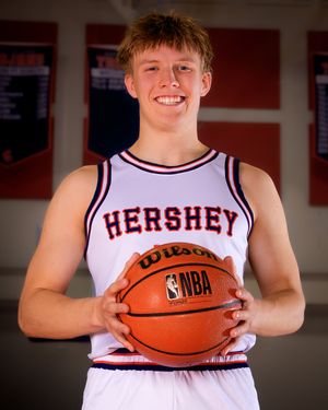 Hershey High School boys basketball player in white jersey holding basketball, individual portrait, team photo day.