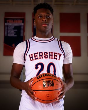 Hershey High School boys basketball player in white jersey holding basketball, individual portrait, team photo day.