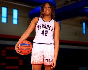 Female Hershey Middle School basketball player in uniform holding basketball, portrait by SportsFox Photography, team photo day.