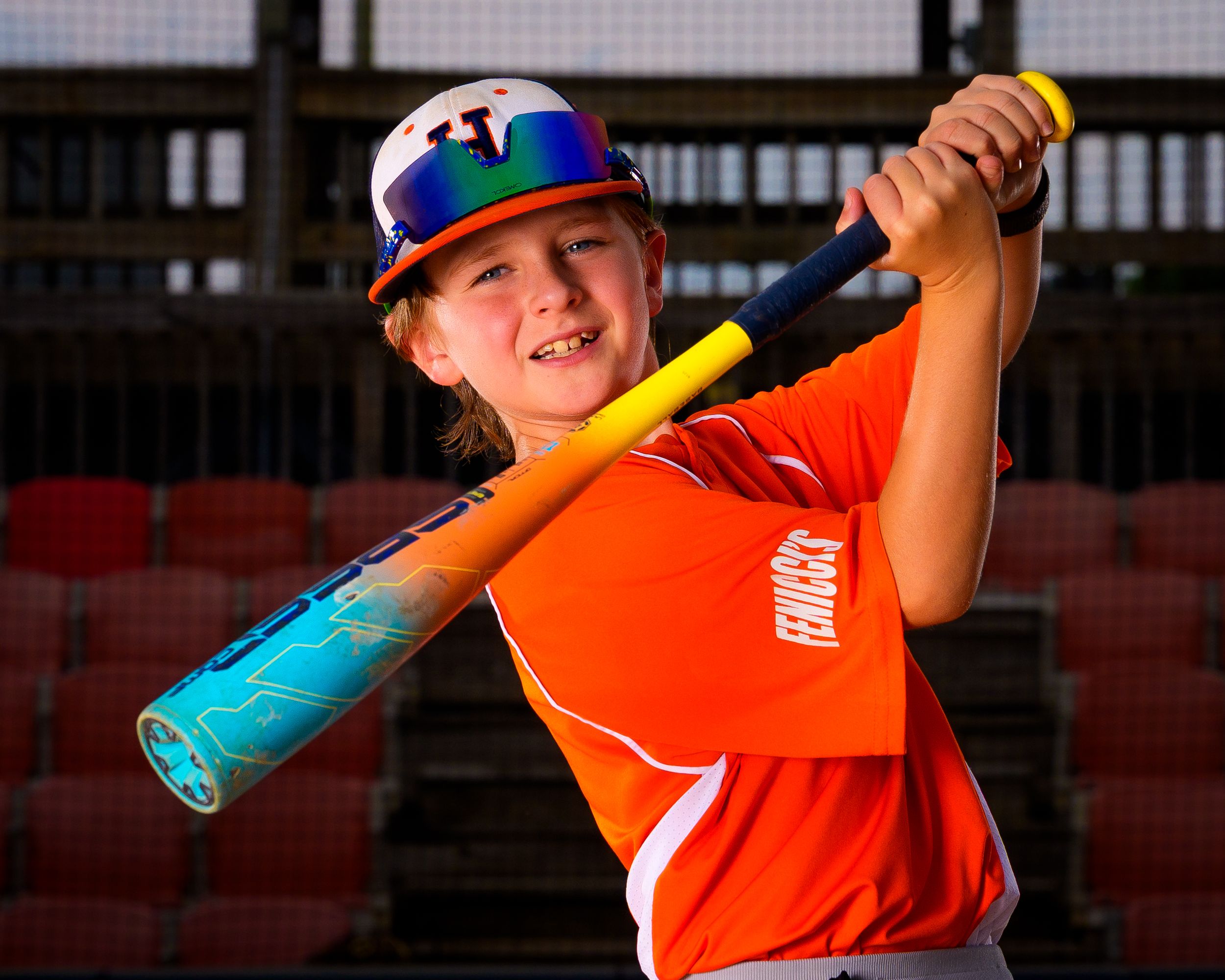 Little League baseball player in orange jersey and blue helmet, posing with bat, team photo day portrait, Hershey PA.