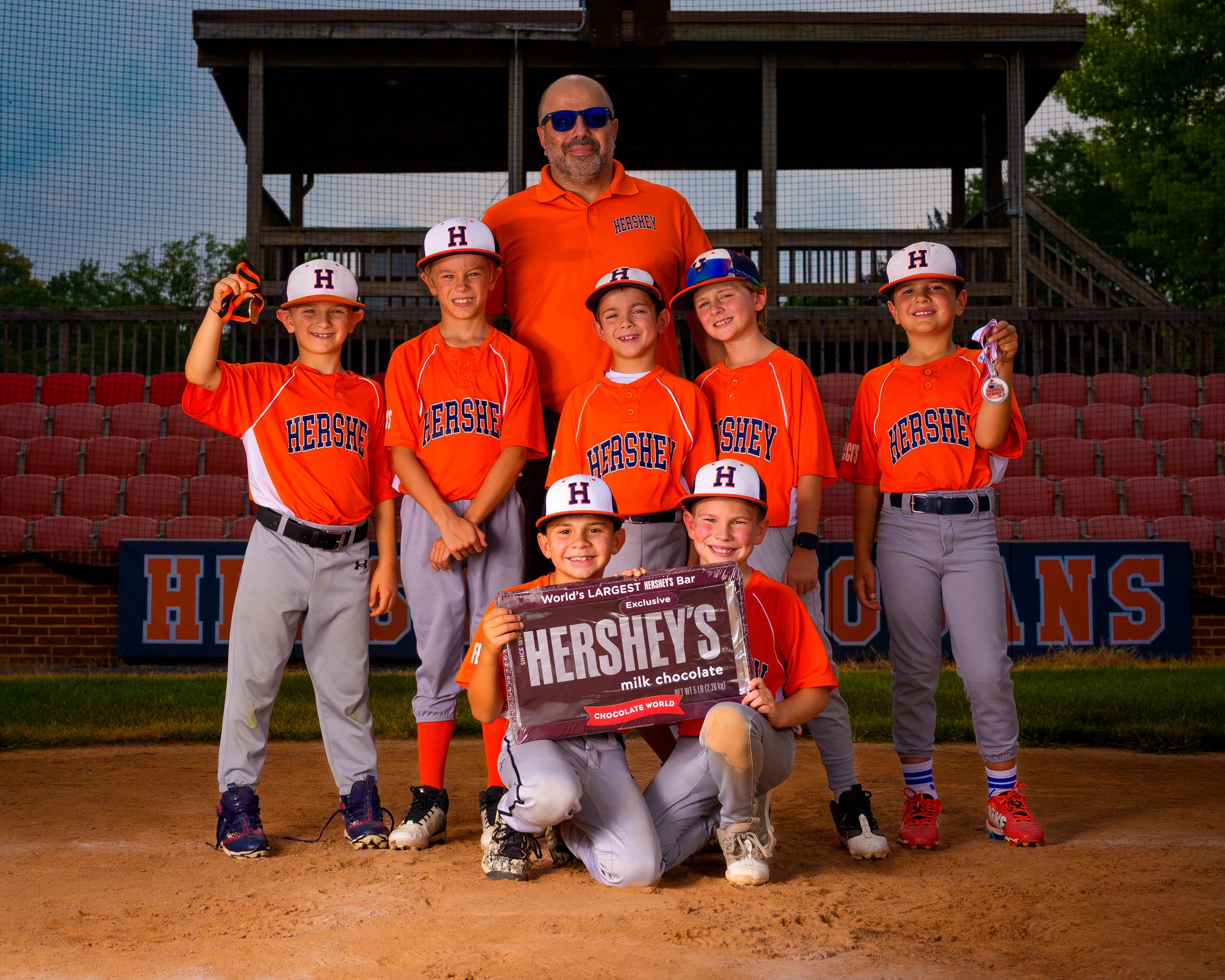 Little League baseball team group photo in orange uniforms on the field, team photo day, Hershey PA.
