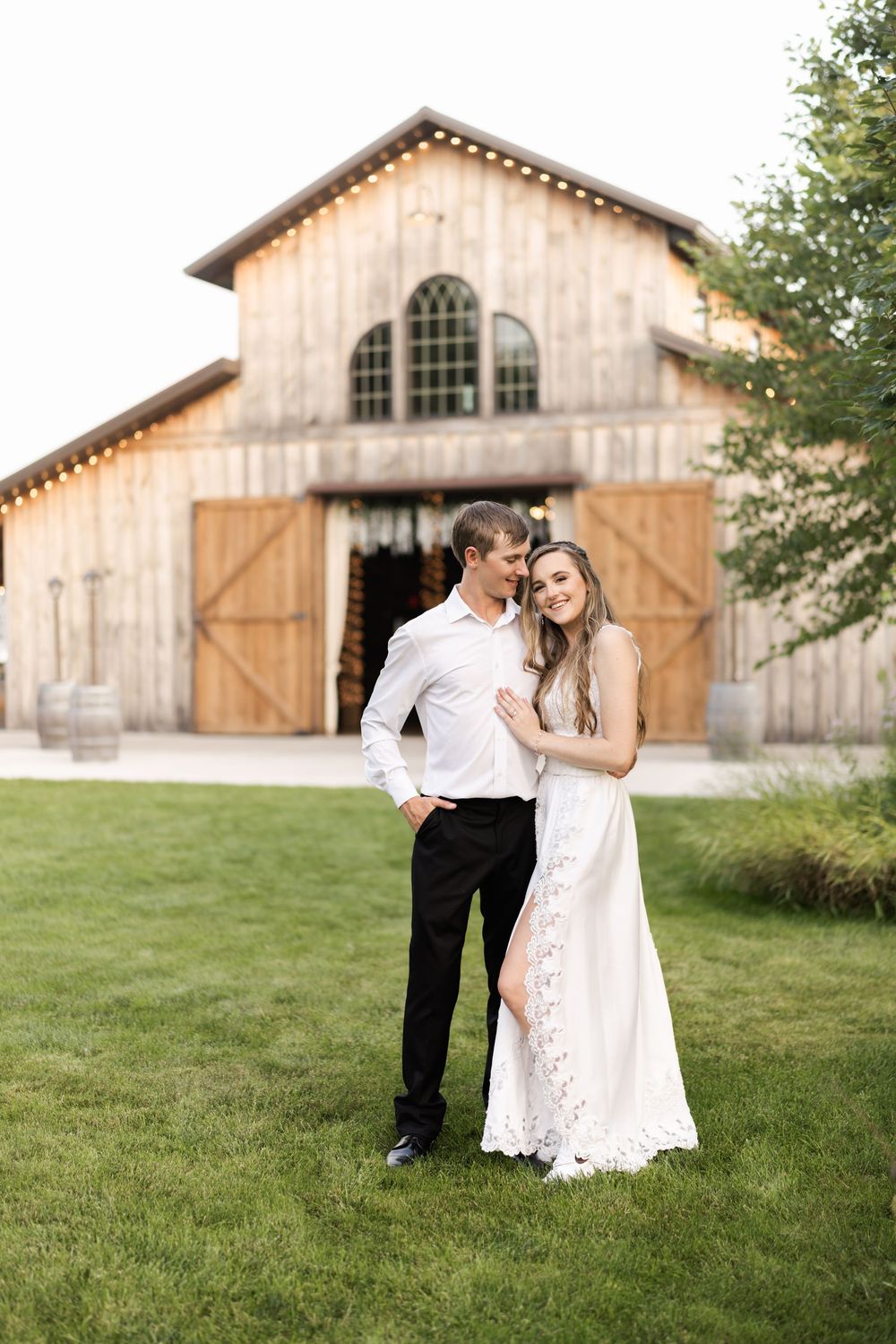 Rustic barn provides backdrop for romantic wedding photos on grassy hill.